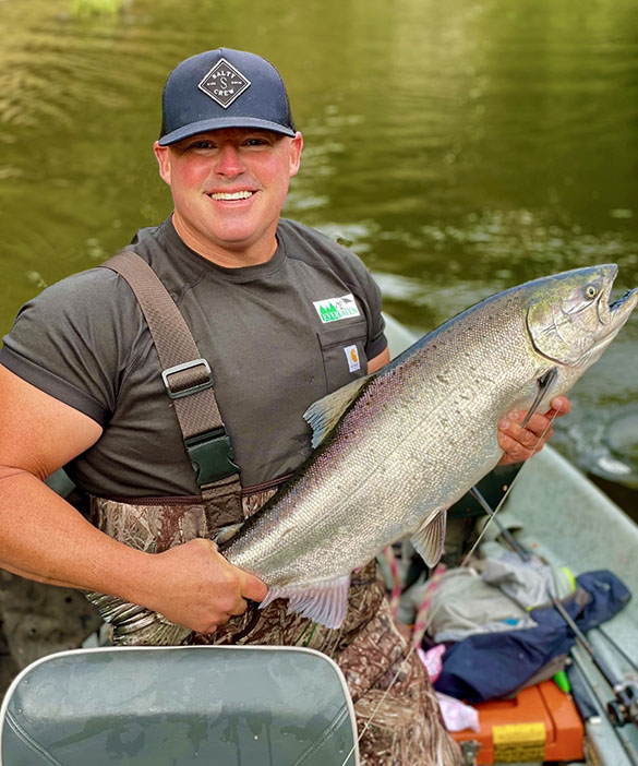 Paradise Landscape Founder, Darren, holding a fish while standing in a boat.